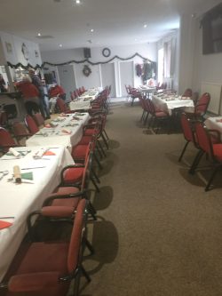 Long row of tables set with place settings and featuring Christmas decorations